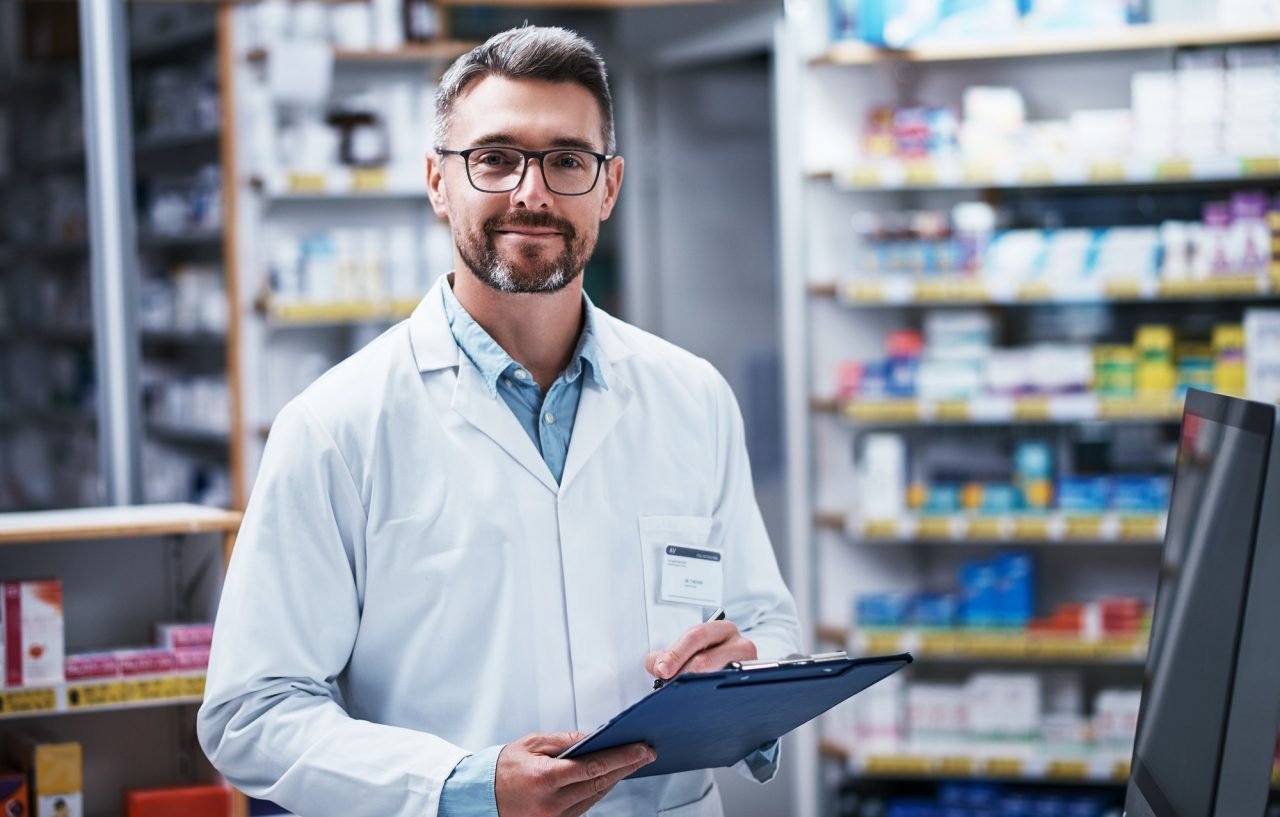portrait of a mature pharmacist writing on a clipboard in a pharmacy